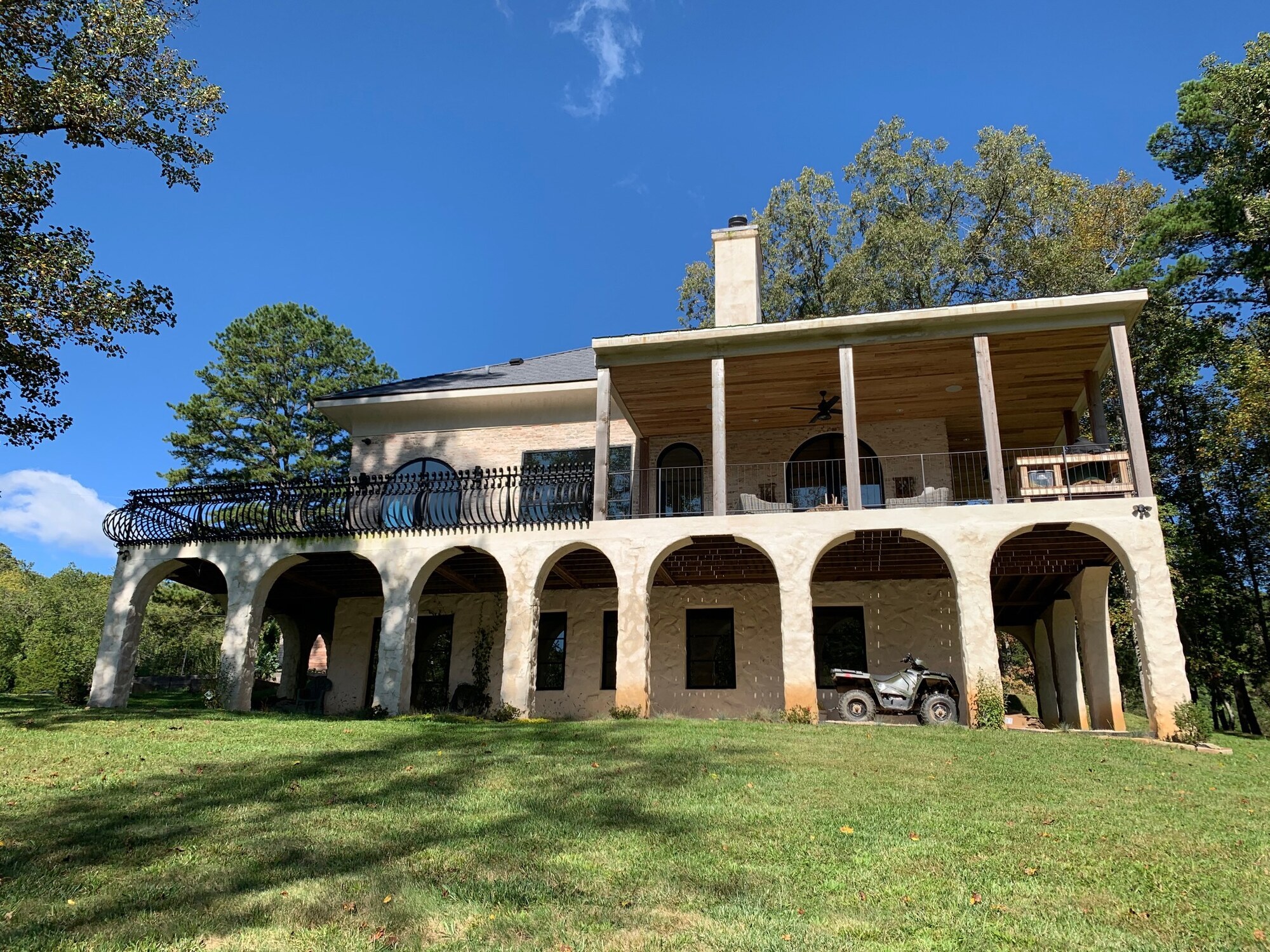 Lime mortar German Schmear across the brick and stone-arched porch exterior at Appalachian Stone Manor, partial-coverage parge coat with the masonry reading through