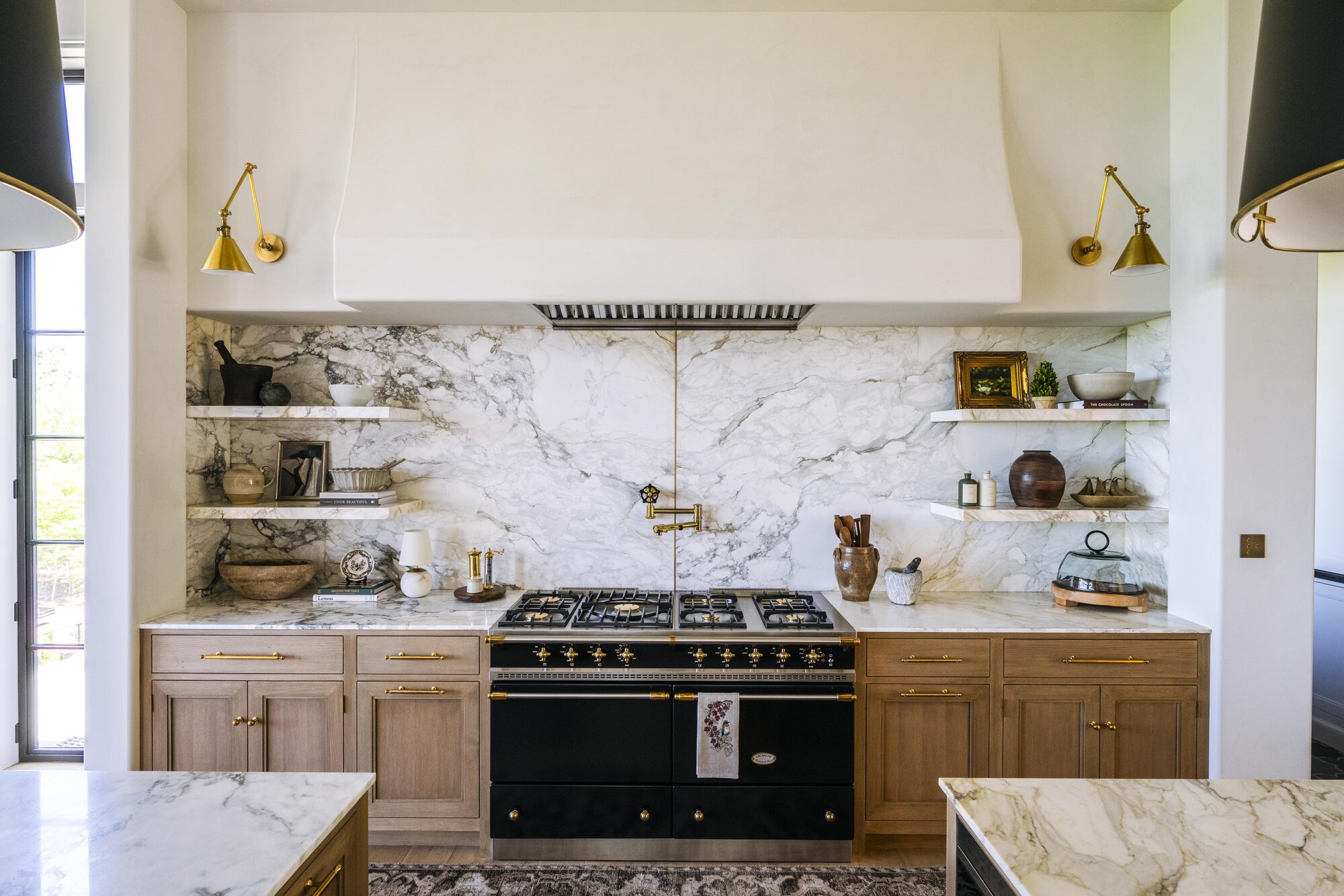 Editorial view of a Tudor residence interior. Layered plaster palette spans cream through warm pink-coral.