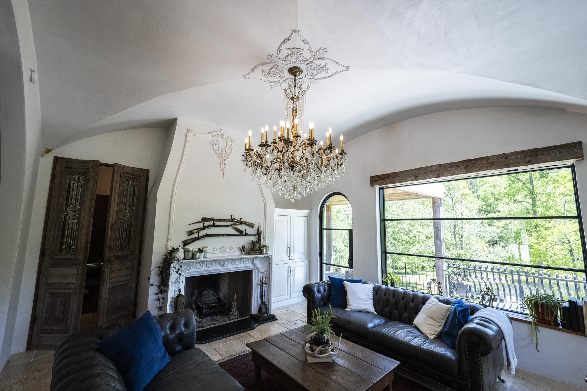 Editorial view of a vaulted living room with crystal chandelier and decorative ceiling ornament.